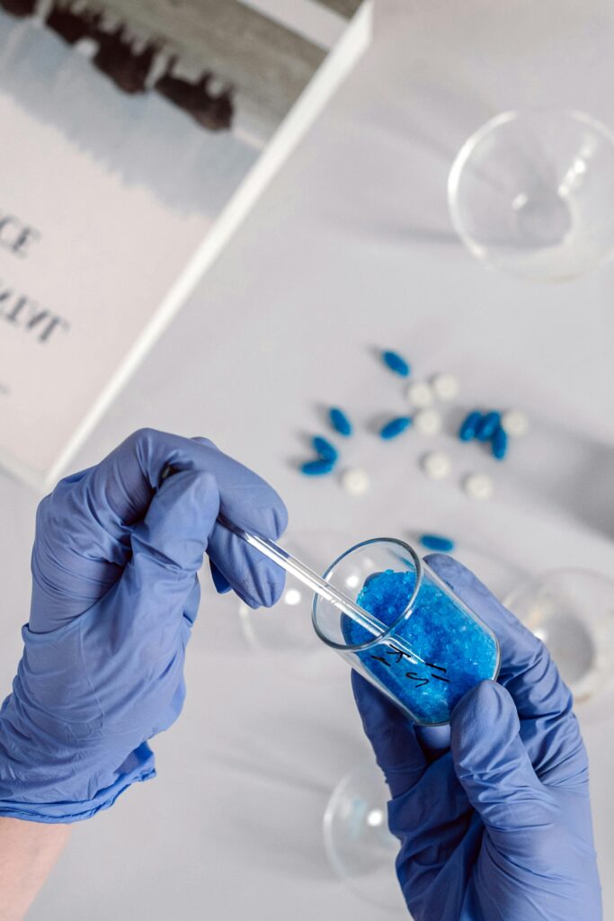Scientist using pipette and beaker with blue crystals in a laboratory.
